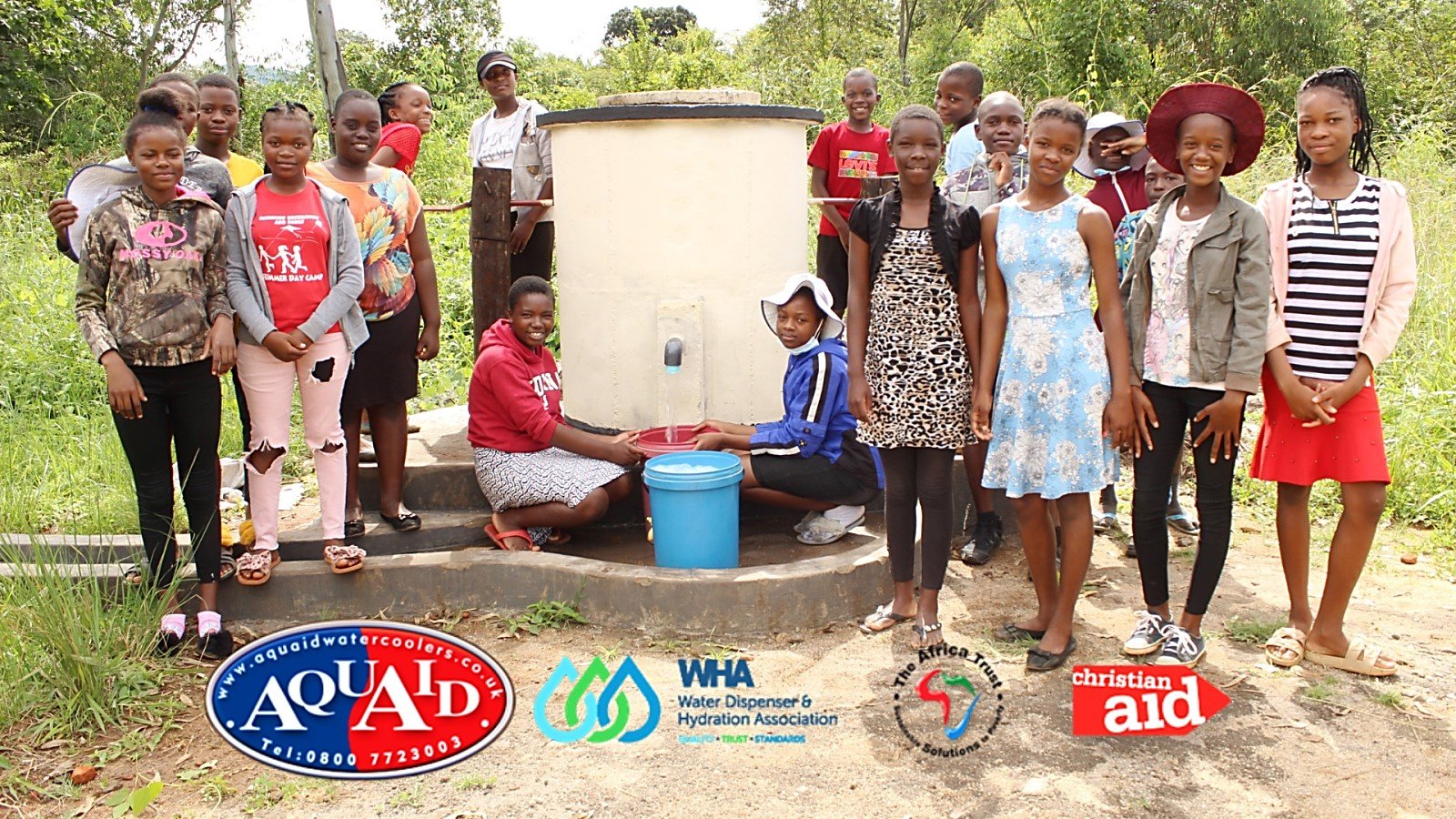 People stand around drinking water fountain supplied by AquAid