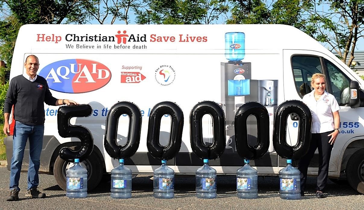 AquAid staff stand infront of their van, celebrating 500000 donations